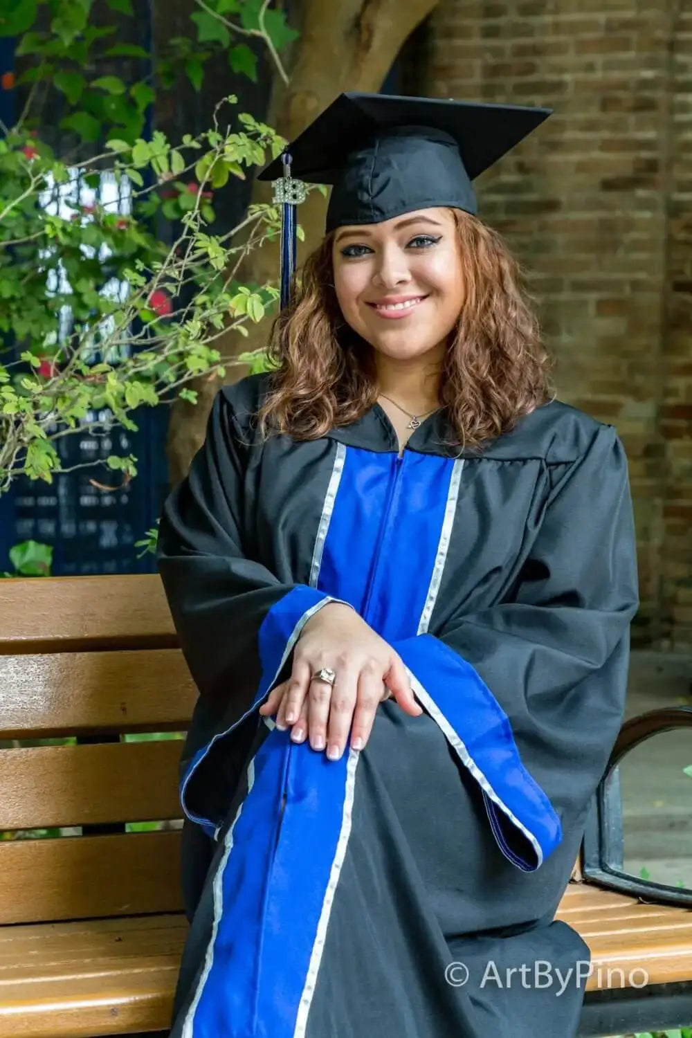 Black graduation gown with vibrant blue accents and satin trim, paired with a matching black cap.