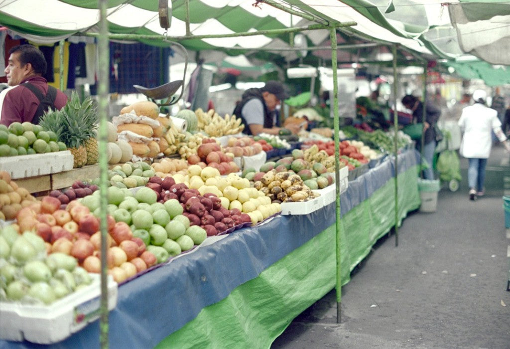 Pentax K1000 / 35mm + Reflx Lab 200T (Kodak Vision 3 200T 5213, ECN-2) + Produce market stall with apples, papayas, and striped awning