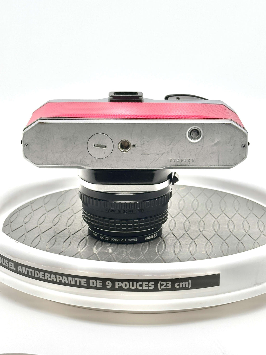 A vintage silver-bodied camera with a vibrant pink textured top panel and a black lens mounted on it.