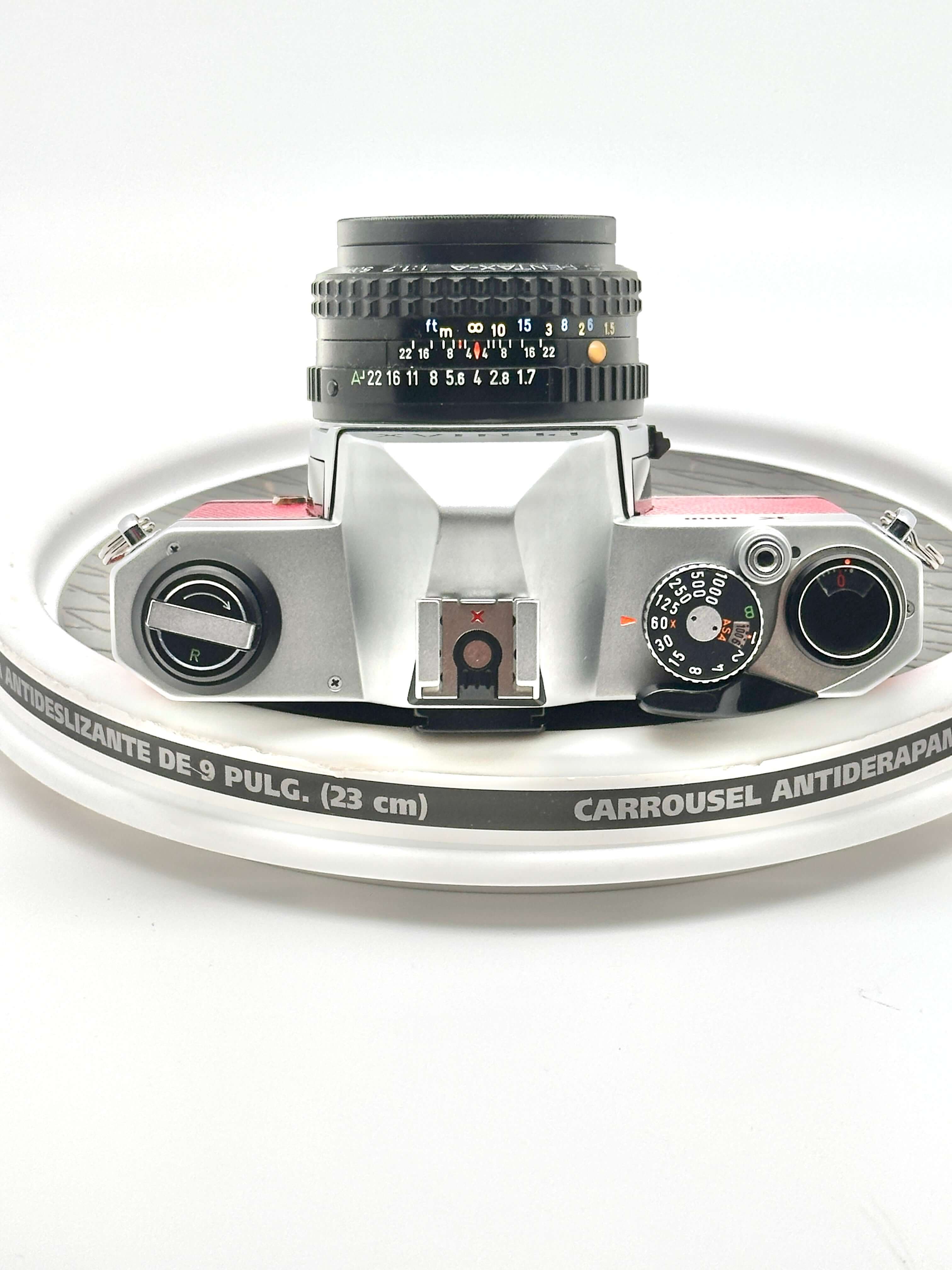 Silver and pink vintage film camera with a black lens, featuring manual focus rings and dials.