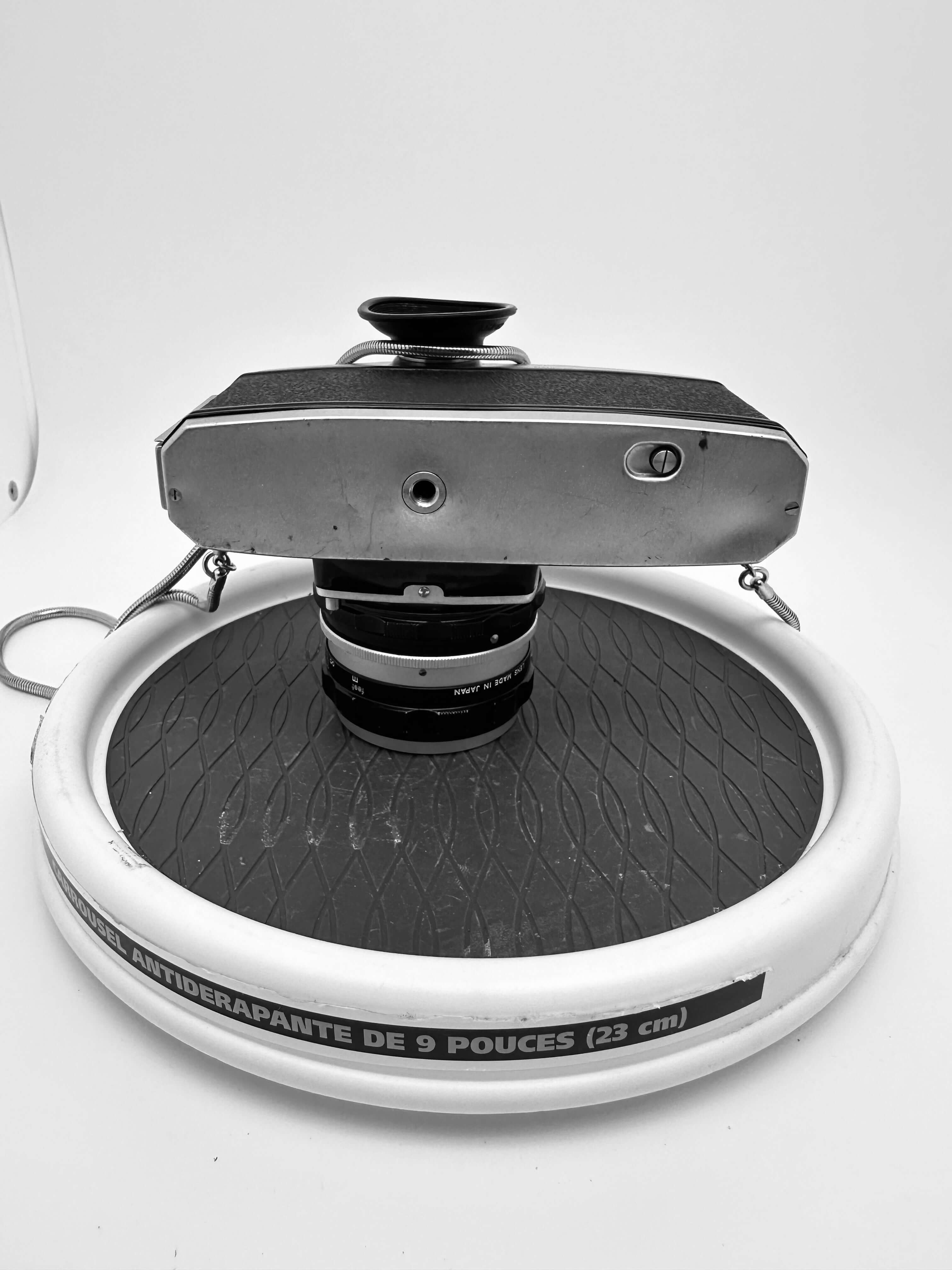 Vintage silver-bodied camera with a textured black top and lens mounted on an anti-slip circular stand.