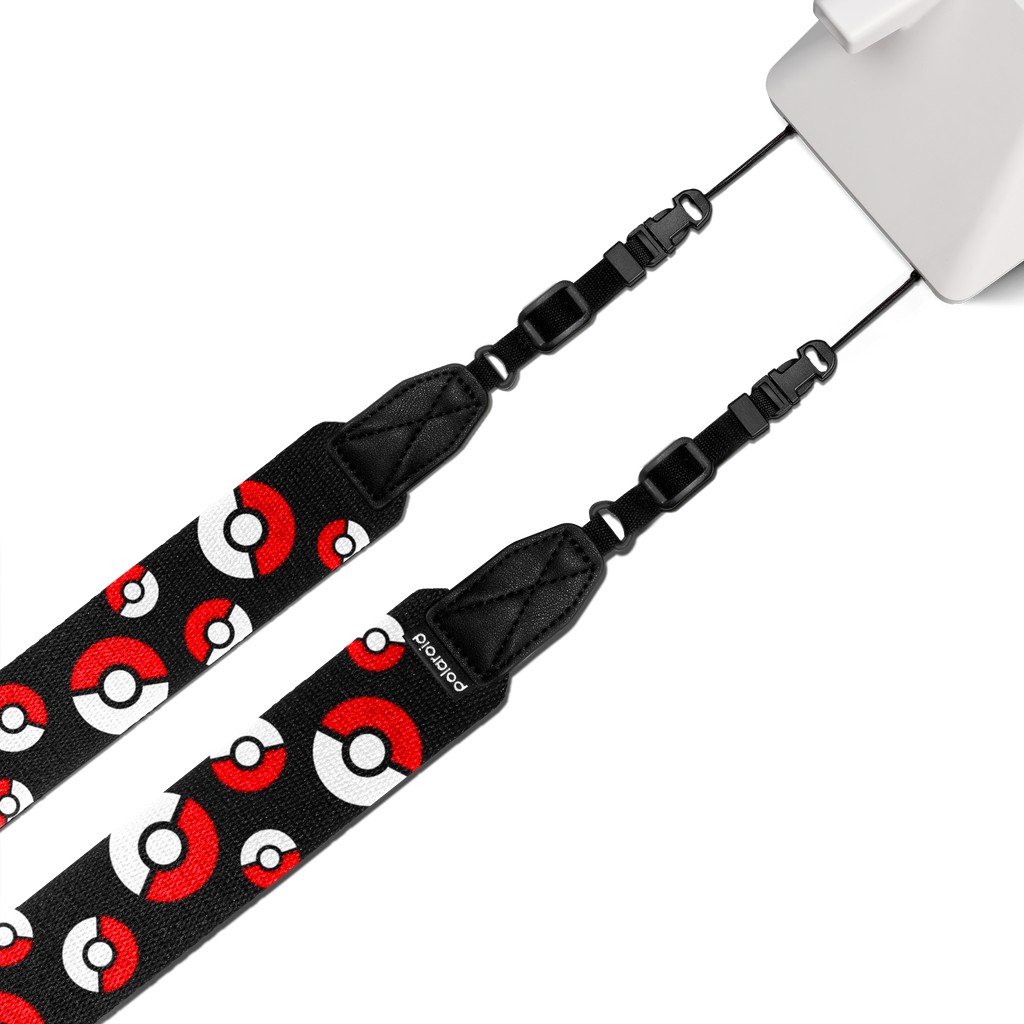 Polaroid flat camera strap in red, white and black Poké Ball design attached to a Polaroid instant camera