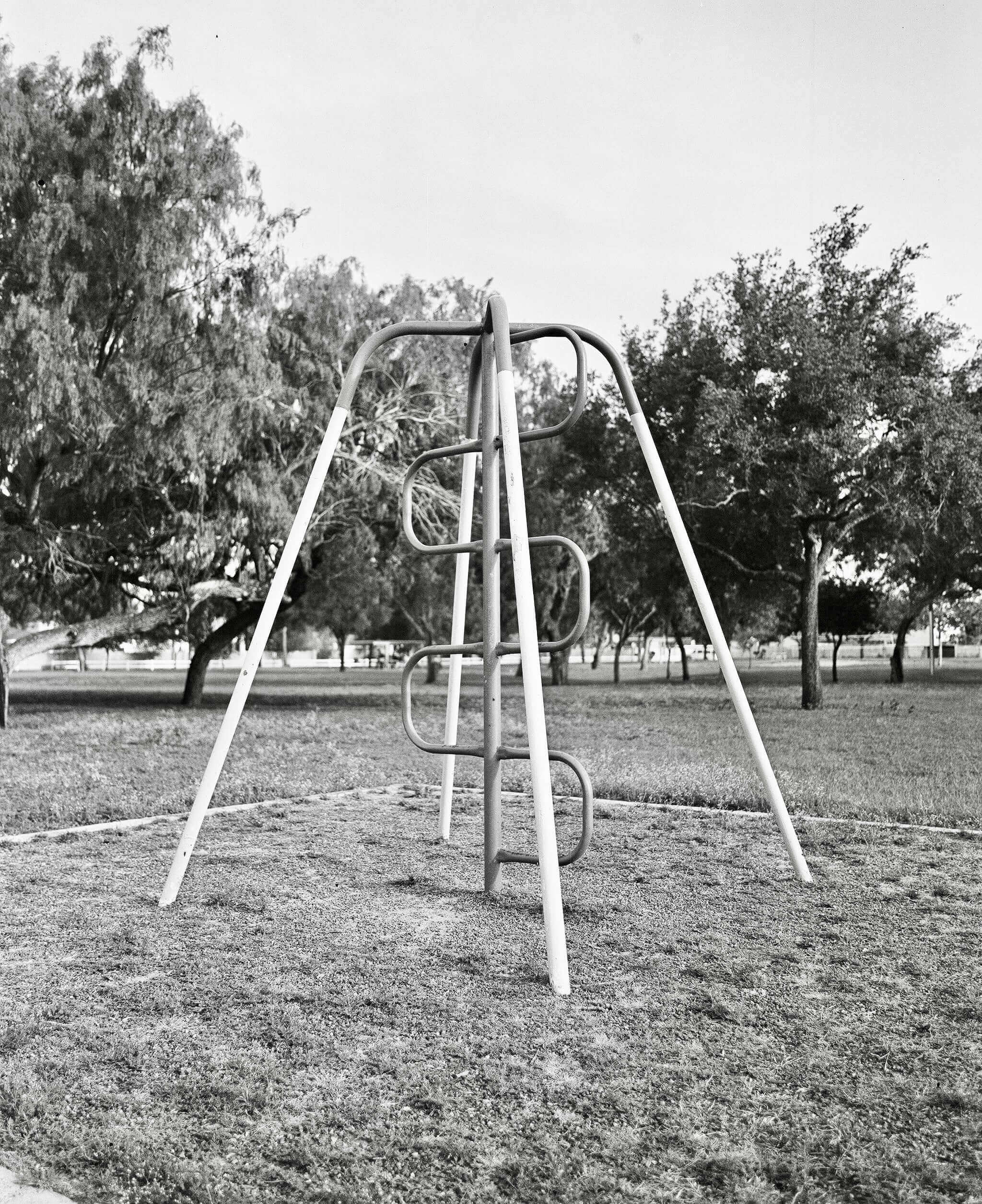 Metallic playground climbing frame with curved rungs and diagonal support beams.
