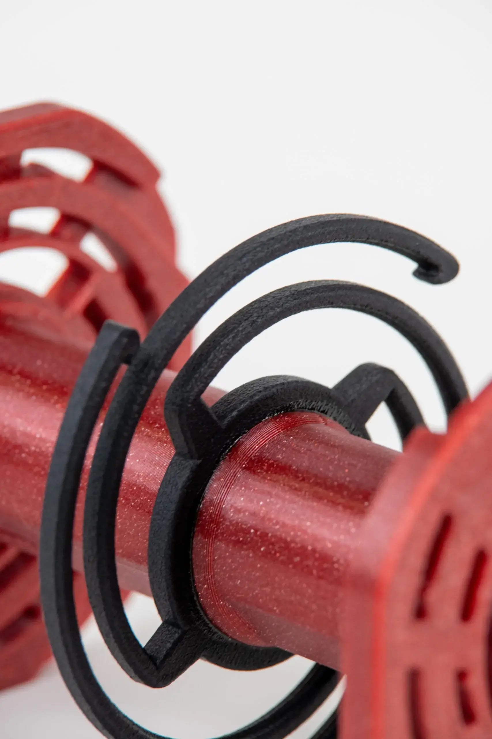 Red and black 3d-printed dumbbell weight holder with a spiral design.