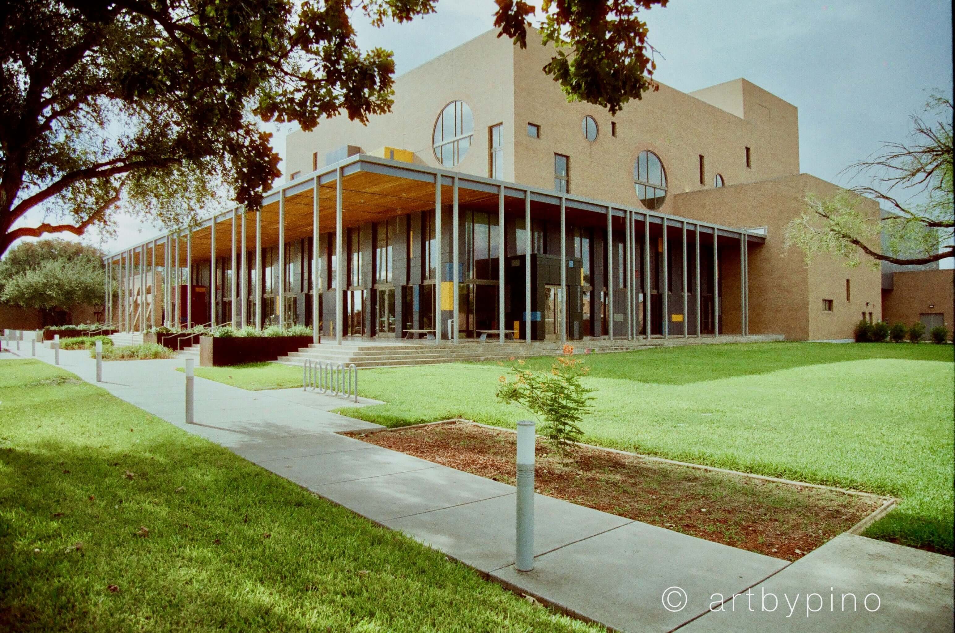 Modern beige brick building with large circular windows and a glass-enclosed entrance.