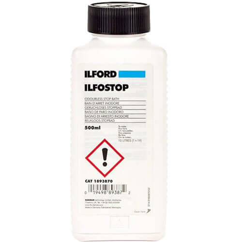 White plastic bottle with black cap, labeled ’ilford ilfostop’ as a perfumes stop bath for photographic processing.