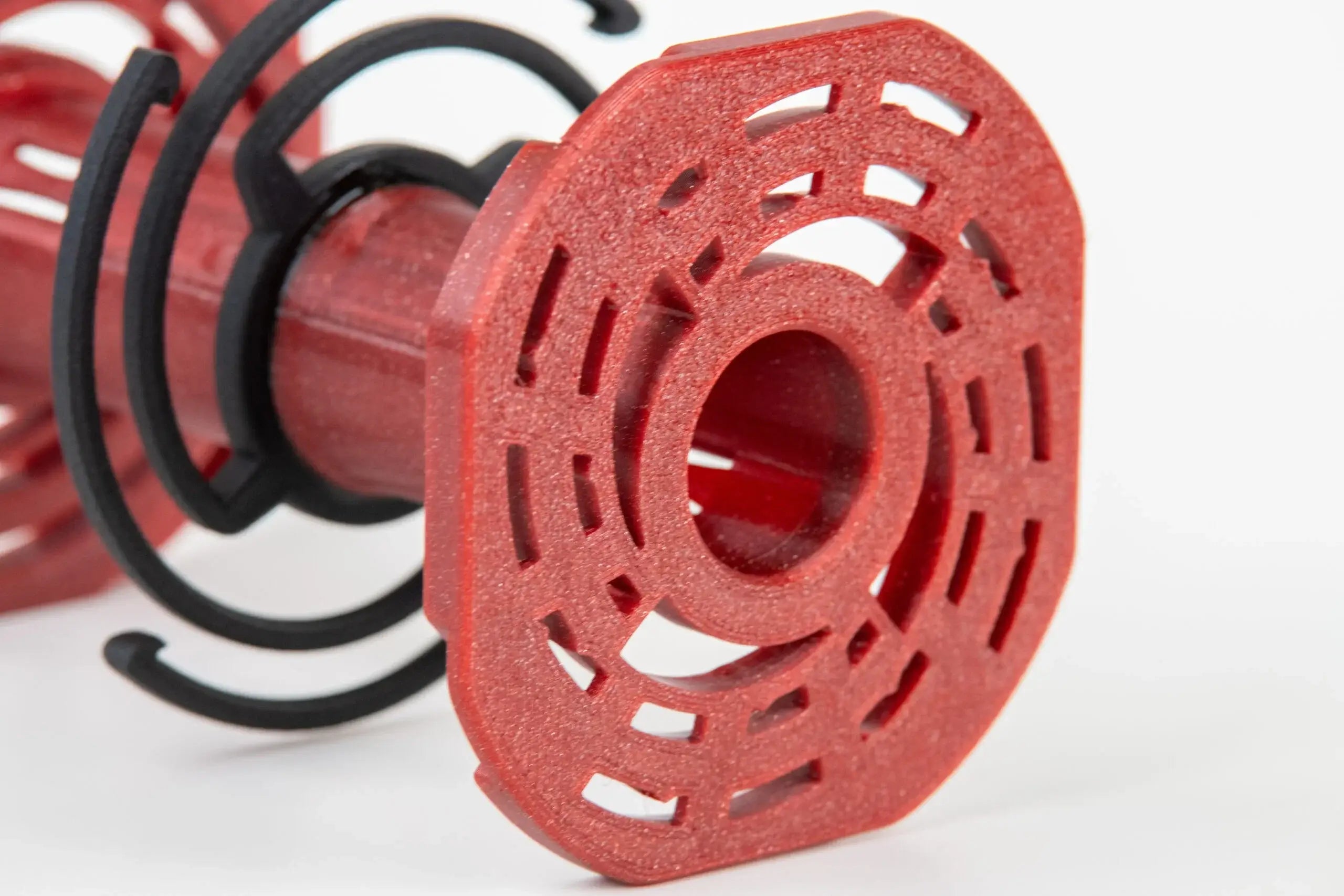 Red plastic spool with a geometric, perforated design and black spiral bands.