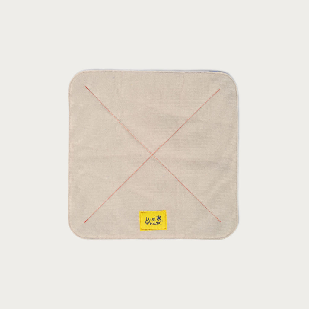 Long Weekend padded camera wrap laid flat, creme exterior with red cross stitching and yellow logo patch