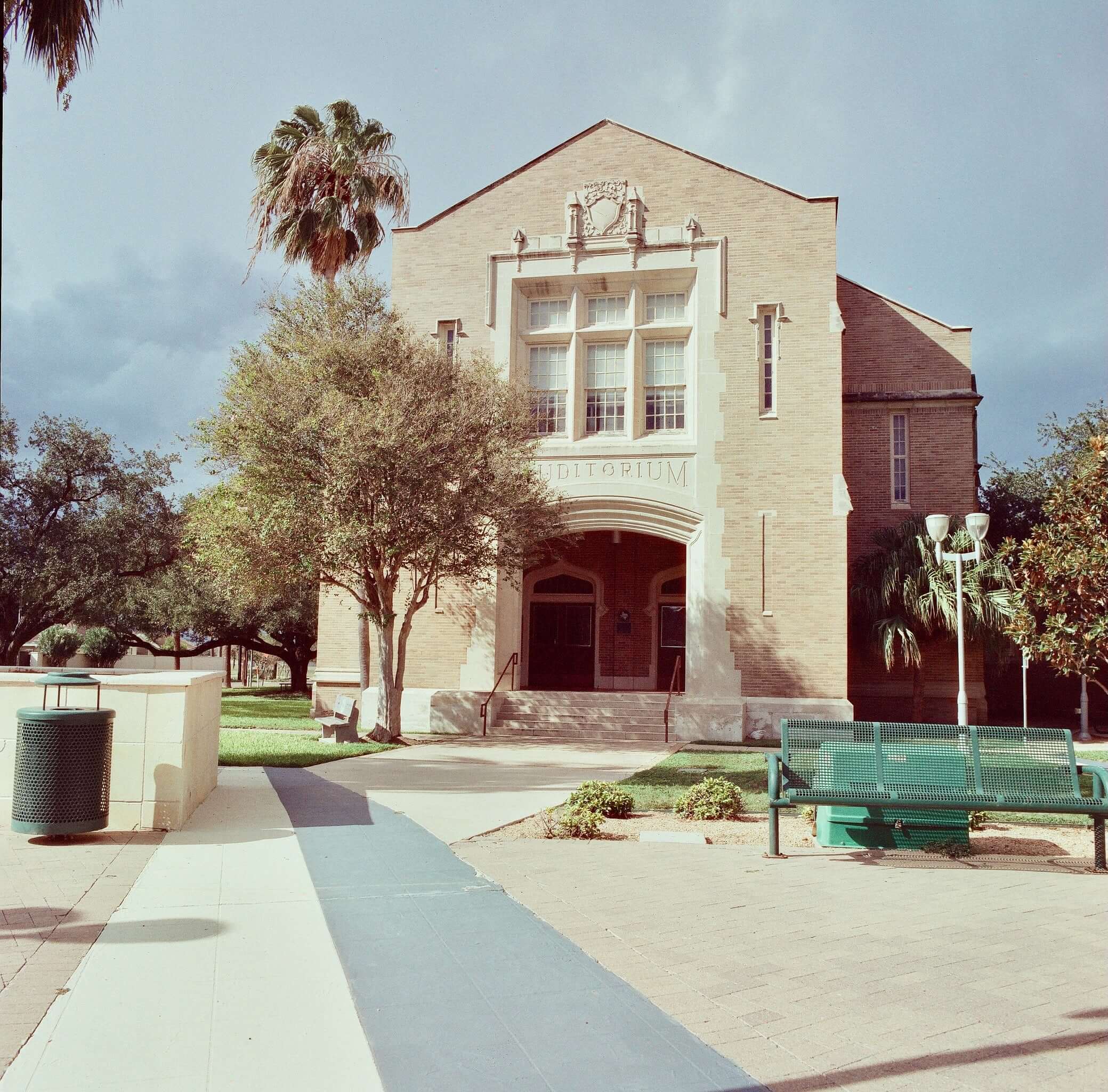 Beige brick building with arched entrance and white stone trim, featuring the word ’editioum’ above it.