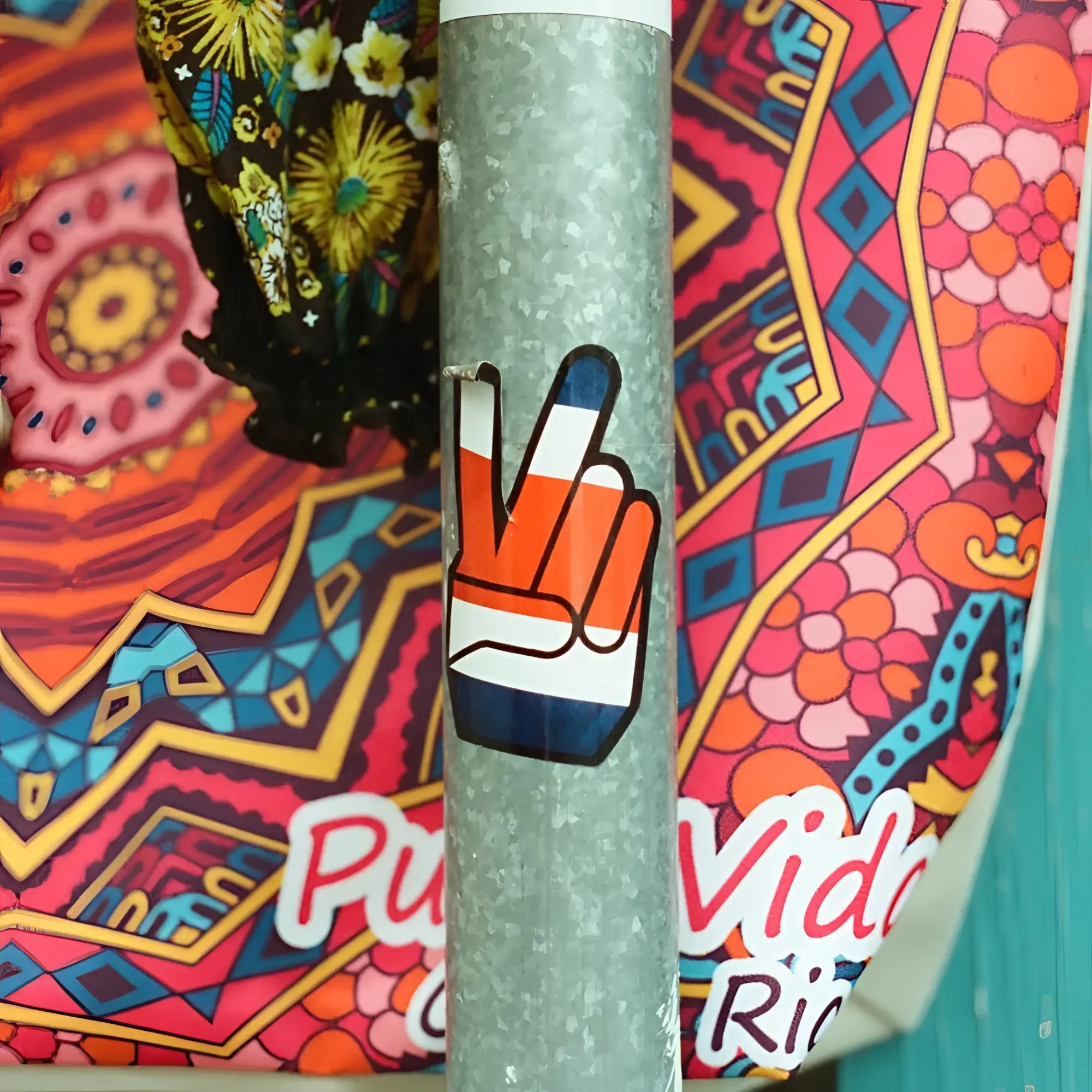 A vibrant orange white and blue peace sign sticker on a textured metallic pole with candido c41 color 400 iso 35mm color negative film