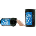 Blue and black cinestill film canisters with one showing a strip of brown photographic film emerging from its open end.