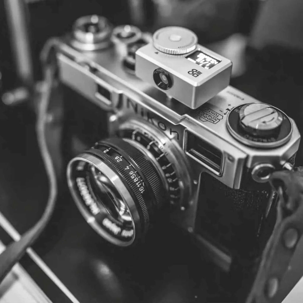 Silver-bodied nikon camera with a mounted lens and top-mounted viewfinder.