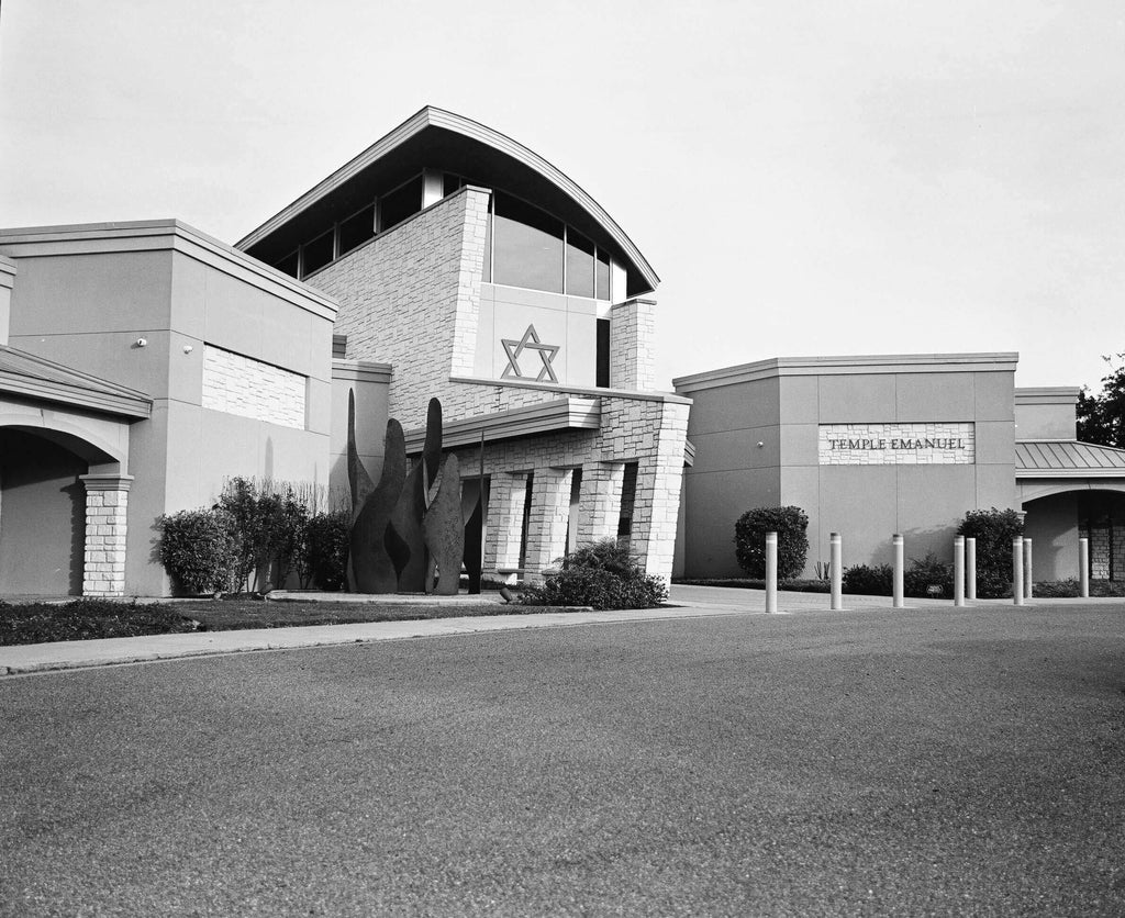 The black-and-white image shows a modern building with stone and concrete architecture, featuring an arched roofline, large windows, and a prominent star of david emblem on the facade.
