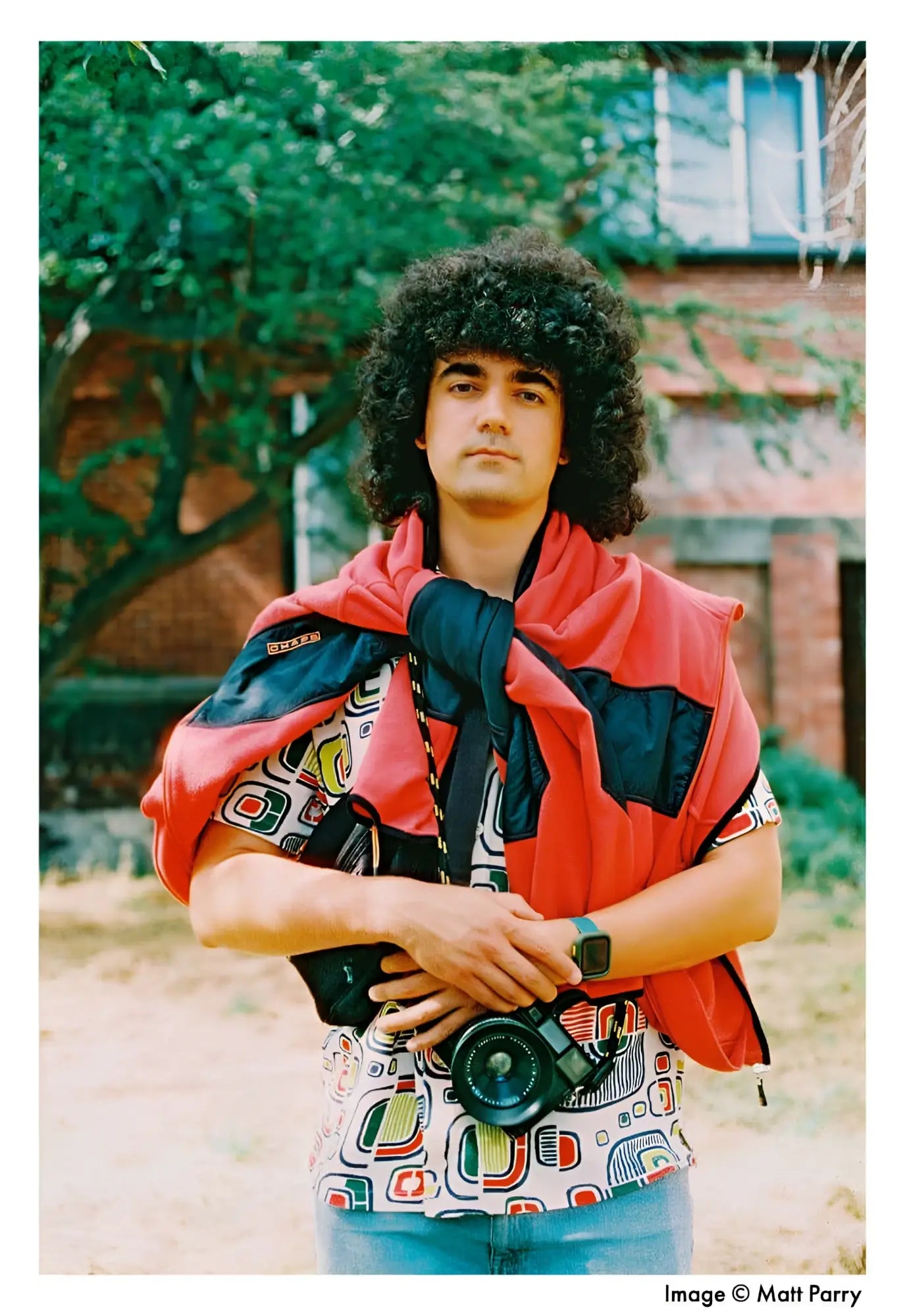 A black camera with a prominent lens, worn around the neck on a strap.