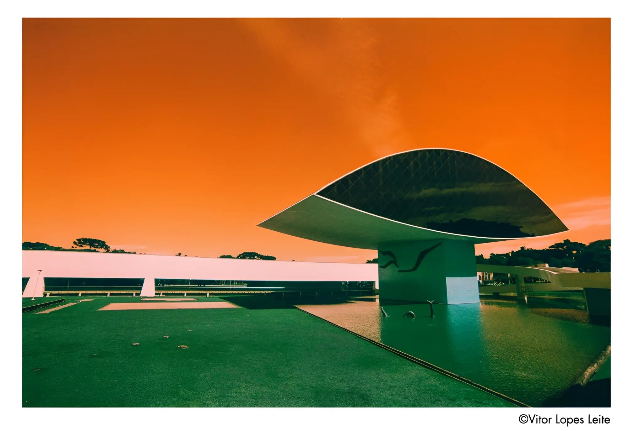 The building features a sleek, modern design with a reflective metallic roof and white structural supports.