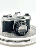 Silver and black asahi pentax k1000 film camera with a textured grip and classic rangefinder design.