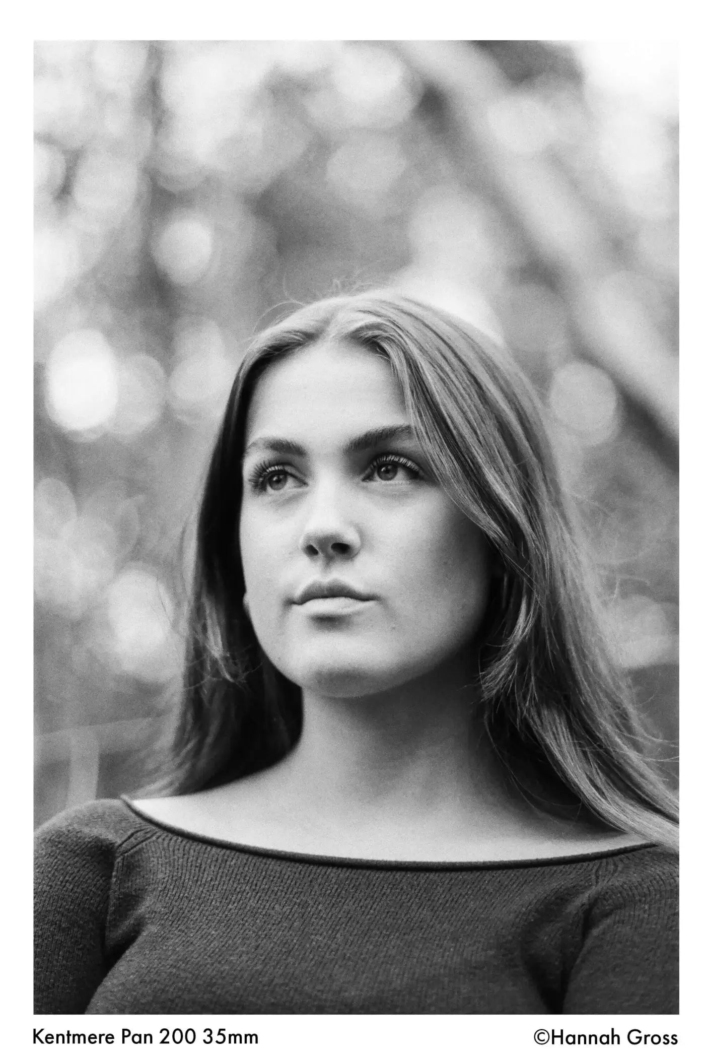 Black-and-white portrait photograph of a woman with long hair wearing an off-the-shoulder knit top.
