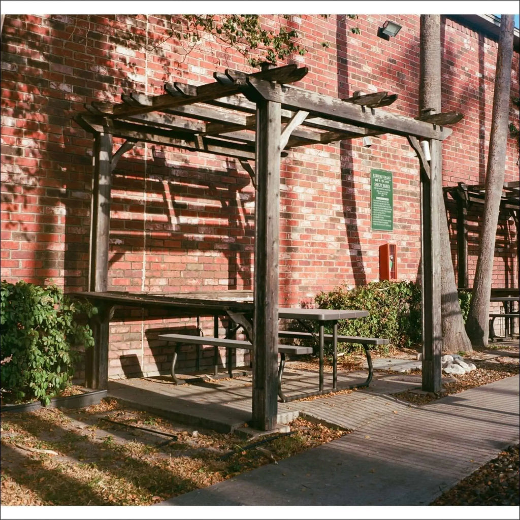 Weathered wooden pergola with a rustic, dark brown finish and simple beam design.