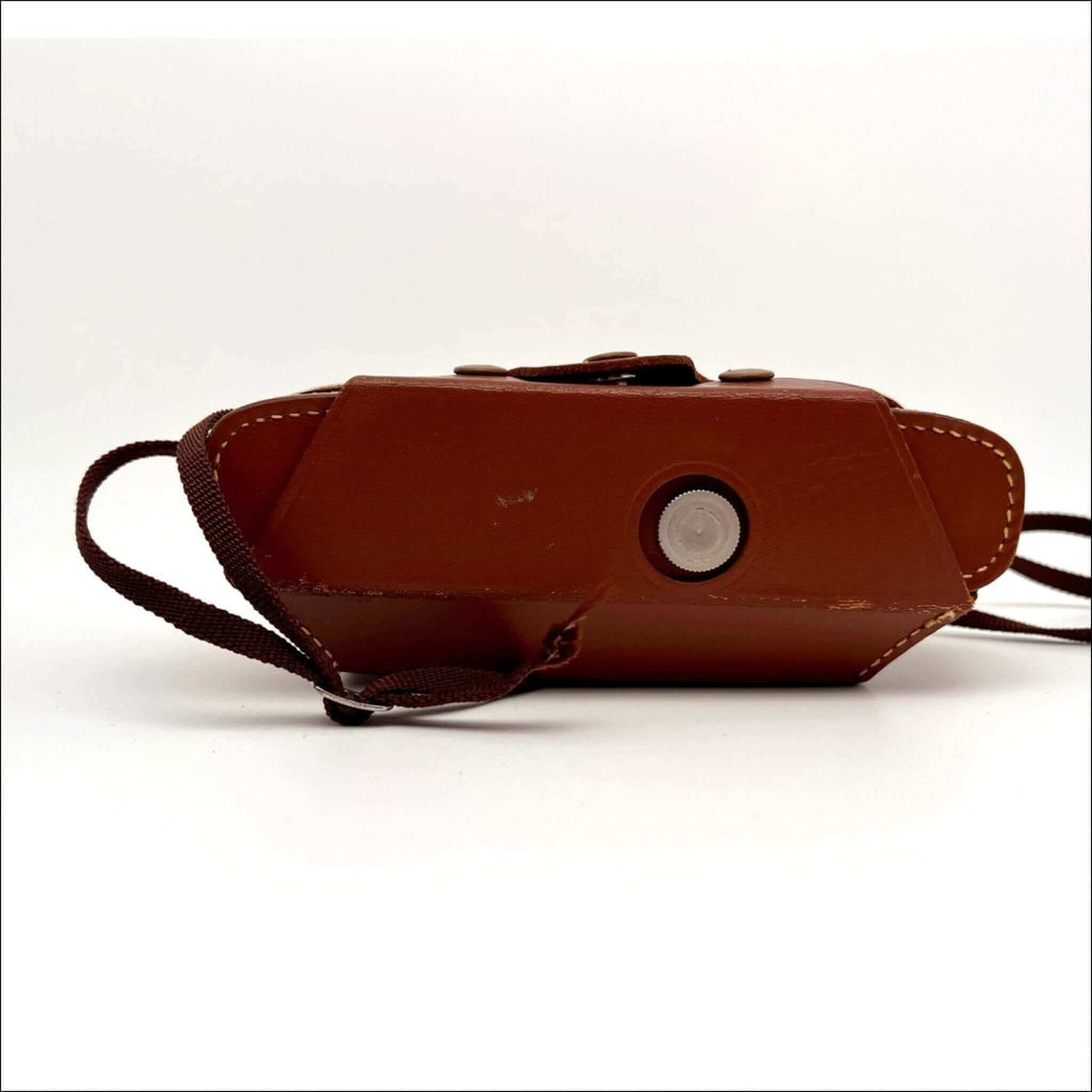 Brown leather camera case with a circular silver button and stitched edges.