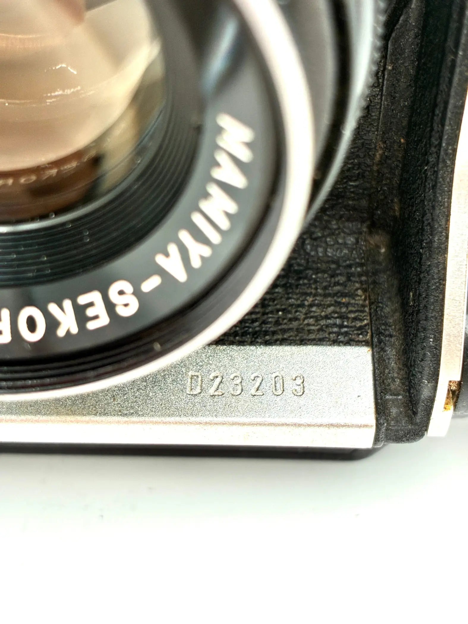 Close-up of a camera lens with 'Mamiya-Sekor' branding on a white background