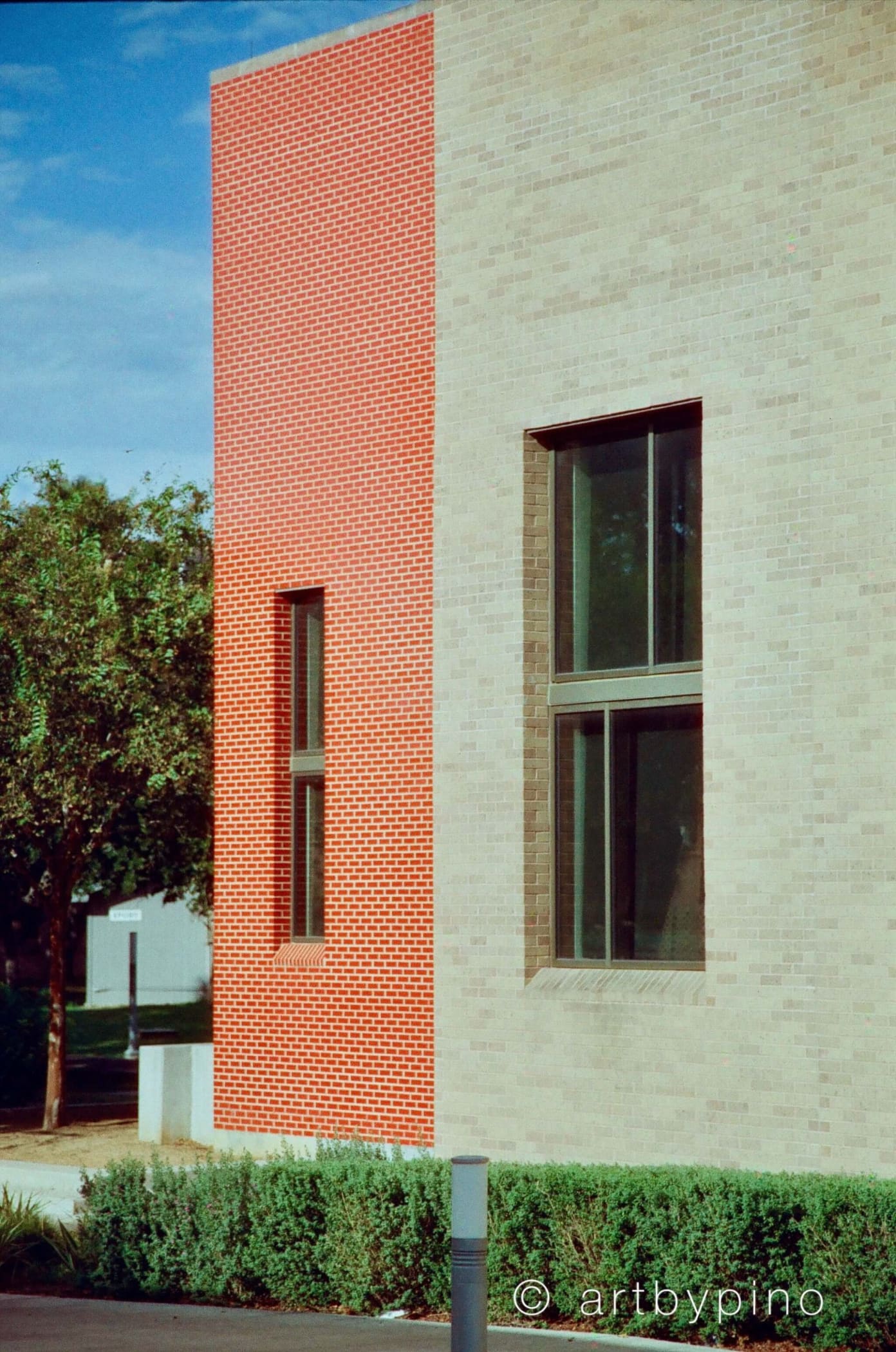 The building features a striking vertical red brick panel contrasting with beige brick walls, accented by dark-framed windows.