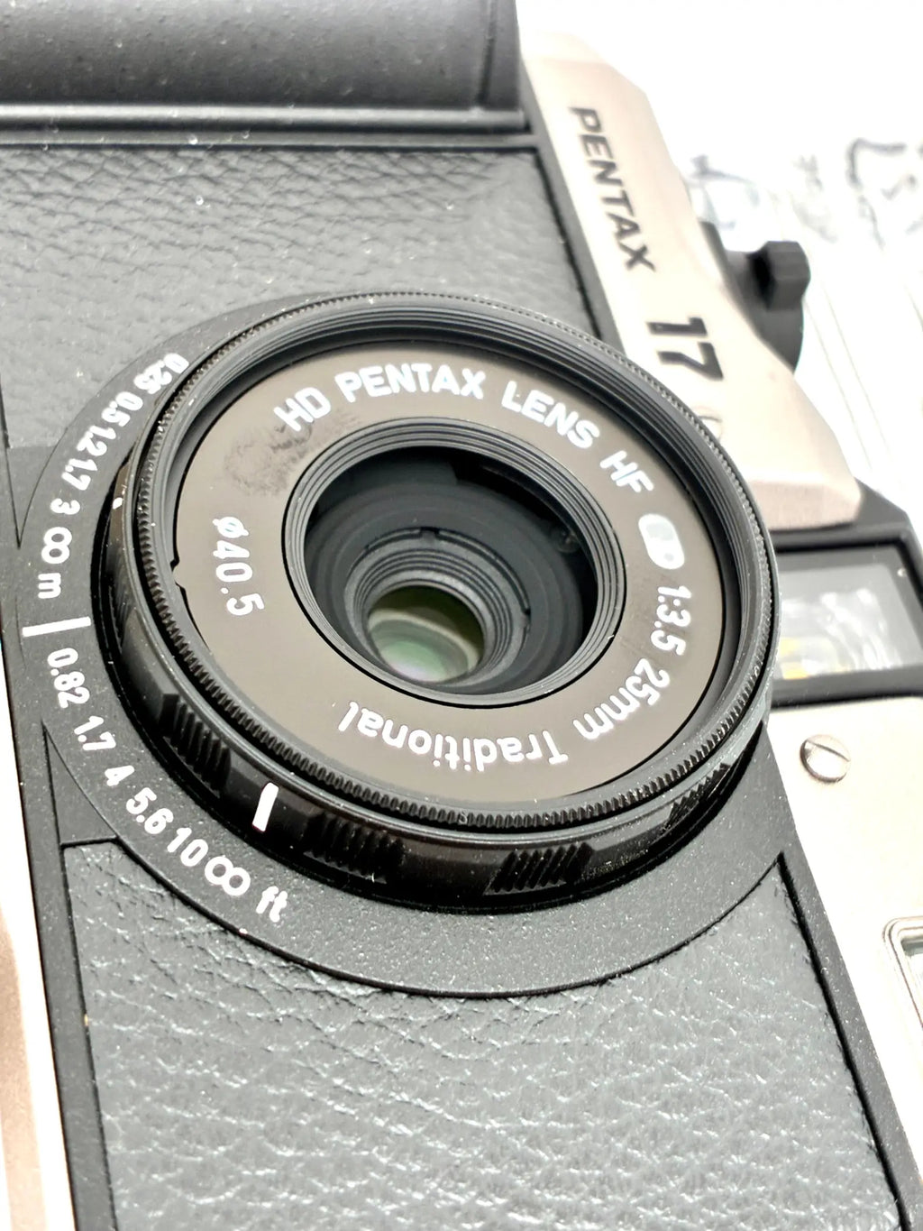 Black hd pentax hf 25mm f3.5 lens with textured grip mounted on pentax 35mm half-frame film camera body open-box