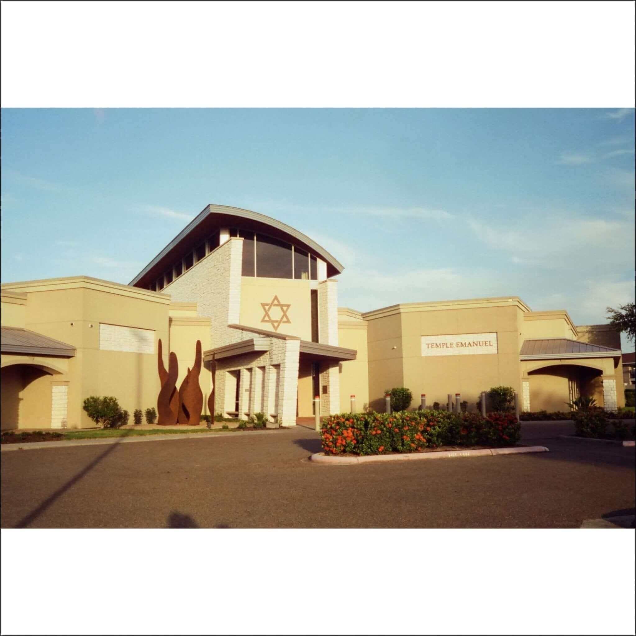 Beige stucco building with a star of david emblem and ’temple emanuel’ sign.
