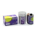 Purple and silver reflex lab 400 daylight 35mm color negative film canister with a partially unspooled roll.