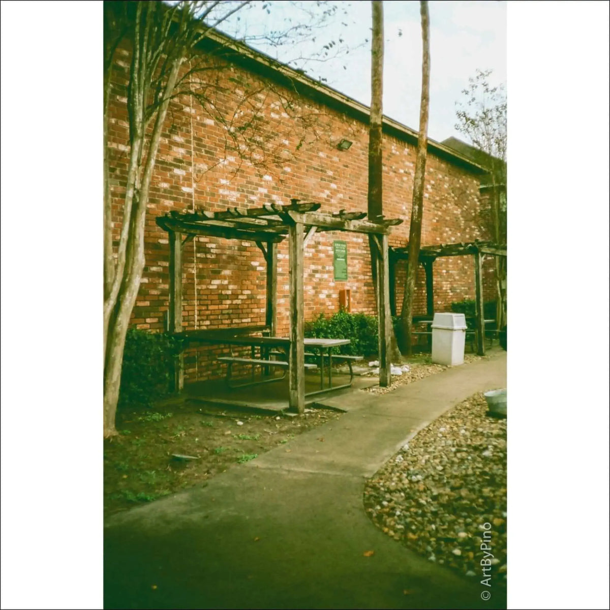 Outdoor picnic area with wooden structures, benches, and a brick wall background.